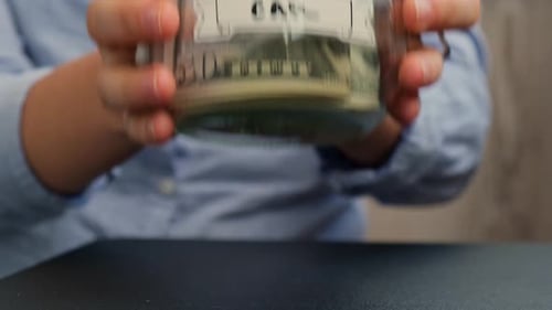 Female Hands Put on Table Glass Jar Full of American Currency Dollars Cash Banknote with Text CAR