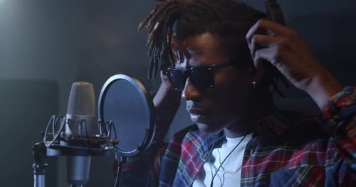 Close Up Portrait of Black Male Musician Walking Towards a Microphone in a Studio, and Putt