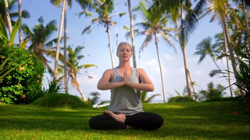 Beautiful Woman Doing Yoga Exercises and Meditation and Holding Hands in Namaste