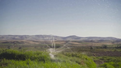 Irrigation system with sprinklers in field in slow motion.