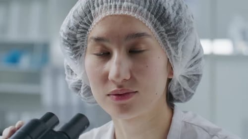 Researcher Looking at Microscope in Lab