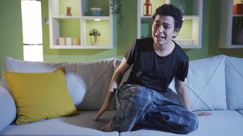 Frightened Young Adult on Couch Watching Scary Movie