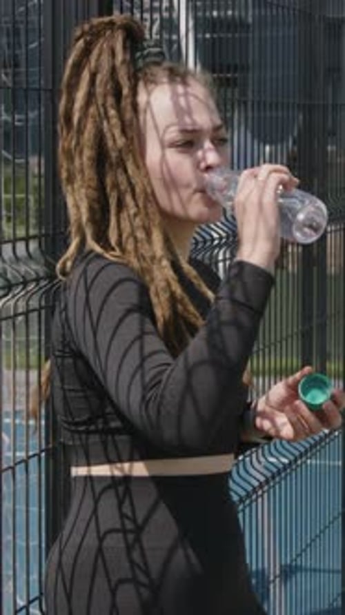 Vertical of Woman Drinking Water After Workout at Recreation Area
