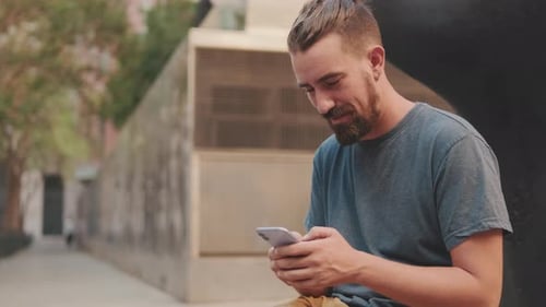 Bearded Man Using Phone in Urban Environment