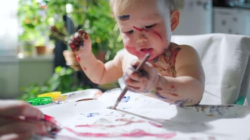 Baby paints, loop. Loopable footage of the infant baby girl painting at home