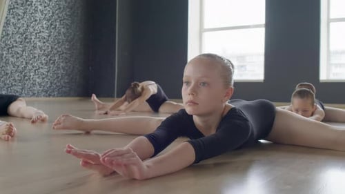 Little Ballerinas Doing Stretching Exercises on Floor