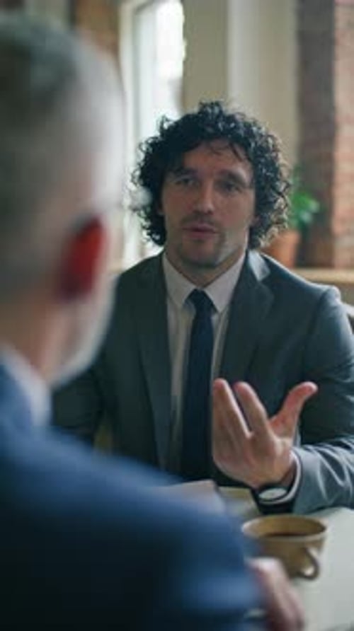 Young Businessman Speaking with Colleague over Coffee during Cafe Meeting
