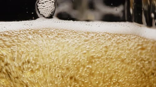 Amber Beer with Bubbles Being Poured Close Up