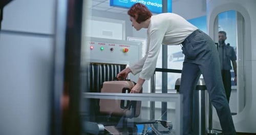 Airport Security Checkpoint Passenger Places Suitcase on Xray Conveyor Belt for Baggage Screening