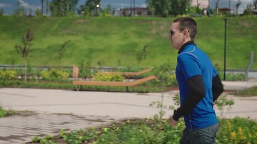 A Successful and Selfconfident Young Man Runs Through a Beautiful and Wellmaintained City Park