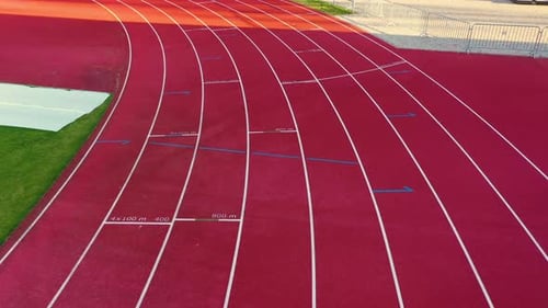 Drone follows eight lane track start line with light across red empty rubber