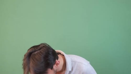 Man Coughing into Hand Against Green Background