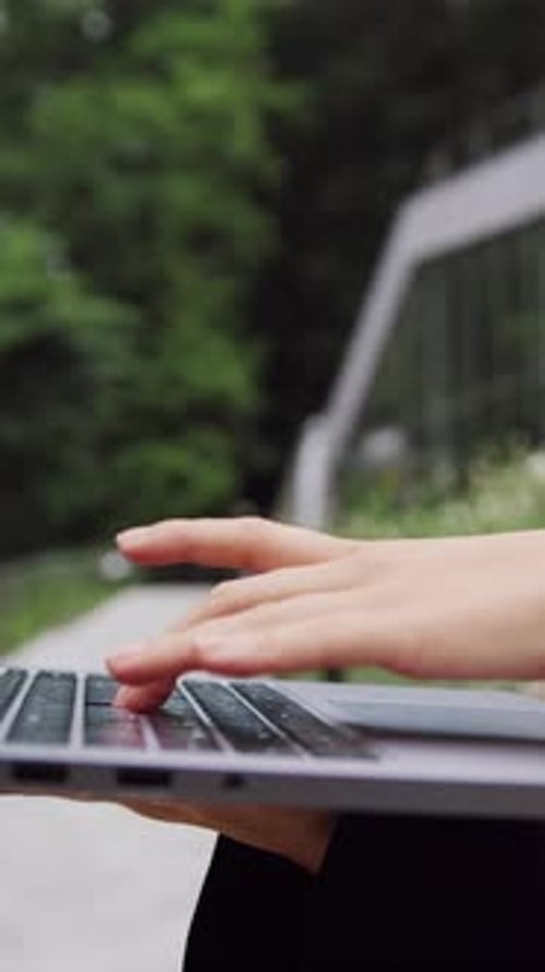 Closeup of Female Professional Hands Typing on a Laptop While Working Online in a City Setting