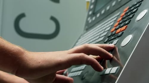 Nahaufnahme der Hände eines Arbeiters, der Parameter für eine CNC-Produktion in einer Fabrik einstellt