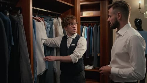 Sales Assistant Helping Customer to Choose Garment in Menswear Shop
