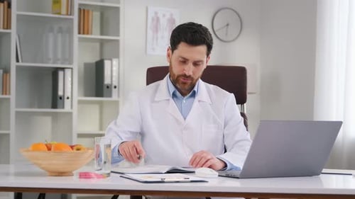 Escribir datos en el documento. Junto a la mesa con el portátil. Un médico con ropa formal está trabajando en el