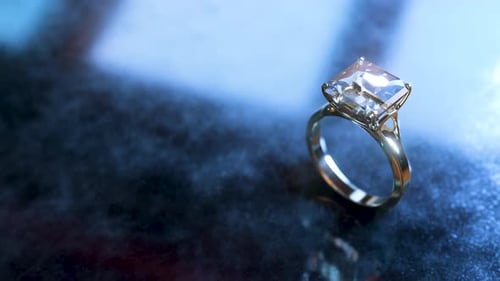 platinum and diamond square ring spins on a metal plate.