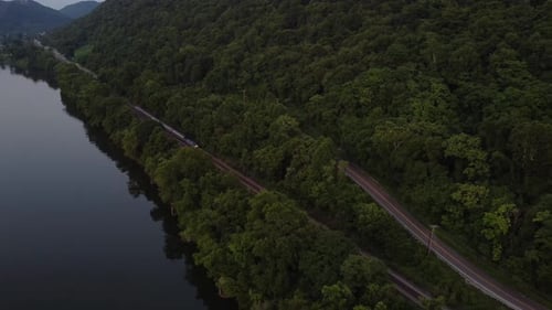 Drone rastreando um trem de passageiros ao longo de uma margem de rio