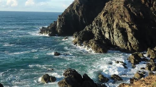 Churning blue water swirling against the rocky coast.