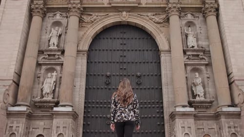 Una mujer caminando hacia la puerta principal de la catedral de Lima en el distrito de Lima, Perú. Tiro panorámico