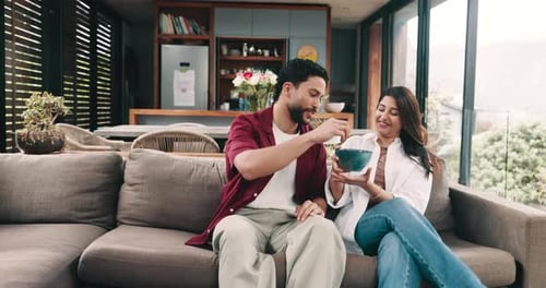 Couple Relaxing on Sofa Sharing Food at Home