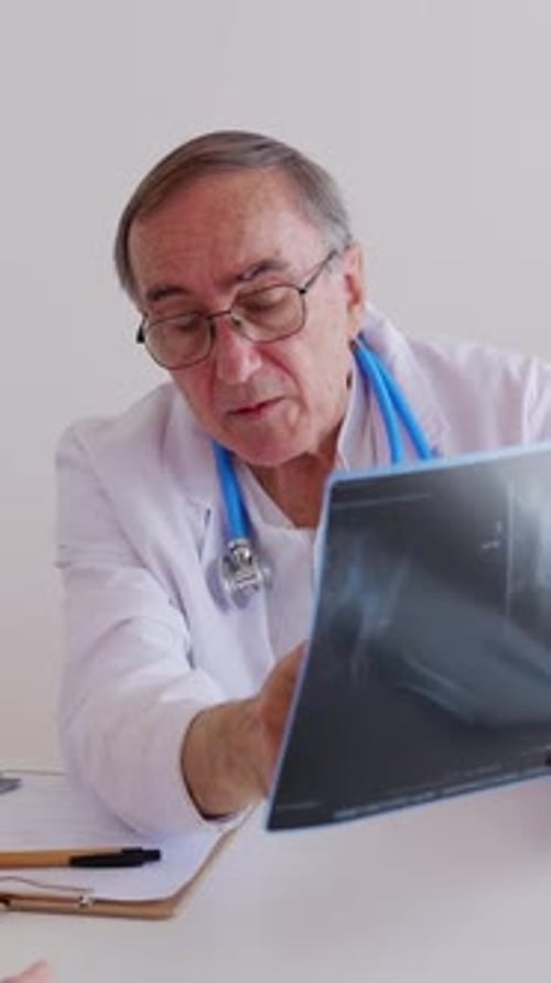 Male Doctor Having Discussing with Patient Over Medical Xray at Hospital