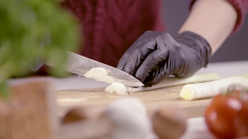 Close-Up of Slicing Fresh Leek Rings with Precision in Rustic Kitchen