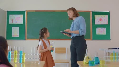 Adorable student learn with teacher in classroom at elementary school.