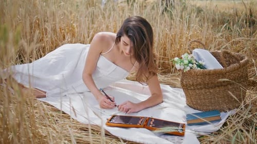 Woman Drawing Outdoors in Golden Wheat Field