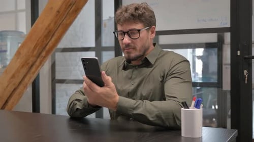 Man Uses Phone in Modern Workplace