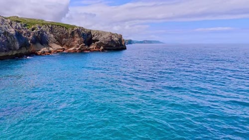 Footage above the blue waterscape at the cliff rocks on the shore.