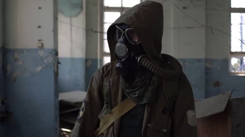 Ein männlicher Tramp-Stalker in einer Gasmaske geht durch ein verlassenes Gebäude