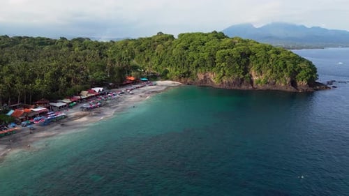 Drone Footage of Tropical Beach in Bali with Palm Lined Coast, Volcanic Shore and Calm Turquoise Sea