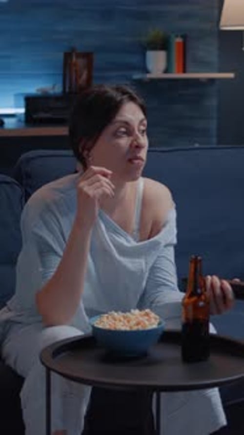 Vertical Video Bored Woman Switching TV Channels Holding Remote Controller Eating Popcorn