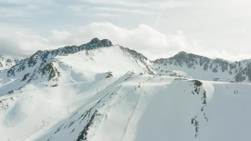 A slight rotation around a mountain top with skiiers and lifts.