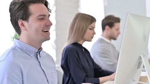 Young Adults Working At Computers In Bright Office