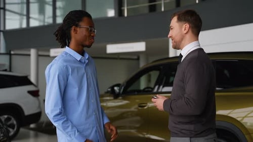 Man Receives Keys from Salesman at Car Dealership