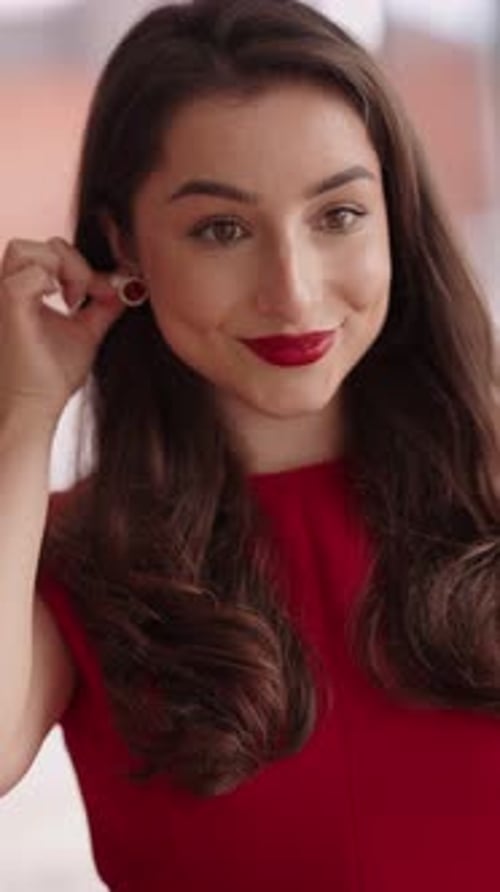Woman Puts on Earrings and Smiles
