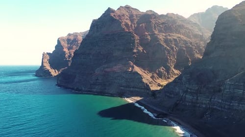 Scenic drone view of virgin beach with torquoise water seascape surrounded by mountain at sunrise