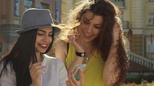 Smiling Women Looking at Phone in the City