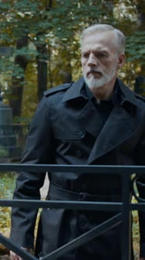 Man Looking Sadly at Tombstone in Cemetery