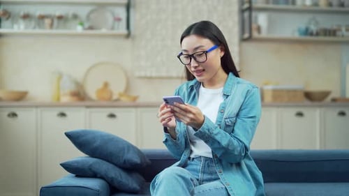 Woman Relaxing on Couch Uses Smartphone