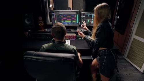 a girl singer and a male sound engineer work together in recording studio to create a new song