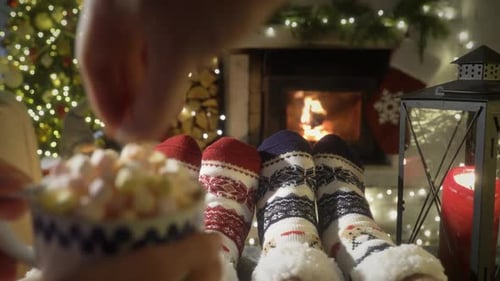 Couple Enjoying By Fireplace and Warming Up Their Feet in Woolen Socks with Christmas Tree and