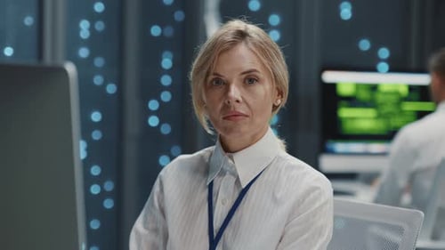 Woman working in data center looks at camera