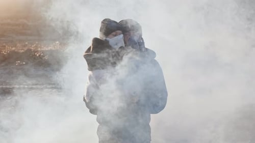 Ein überlebender Vater trägt ihre Tochter in einer Gasmaske und bewegt sich in leeren Toten durch giftige Rauchwolken