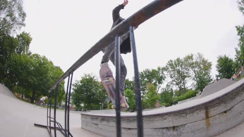 Slow motion low angle skateboarder 180 over a railing