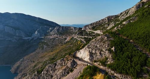 AERIAL: Mountainous winding road on the Makarska riviera, sunny day in Croatia