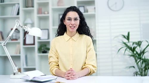 Webcam view. A young woman talking on a video call looking into the camera while sitting in a home o