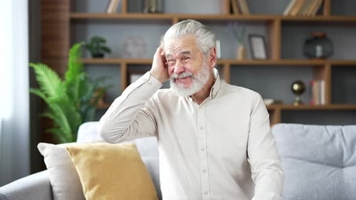 Ohrenschmerzen. Der kranke ältere Mann leidet unter Ohrenschmerzen, wenn er zu Hause auf dem Sofa sitzt. Verärgerte erwachsene reife Frau